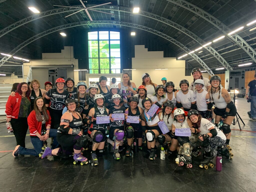 BAD Comets vs Monterey Bay 2025 A group photo of BAD Comets in white jerseys and Monterey Bay Comets in purple jerseys. Several skaters hold up purple bandanas.