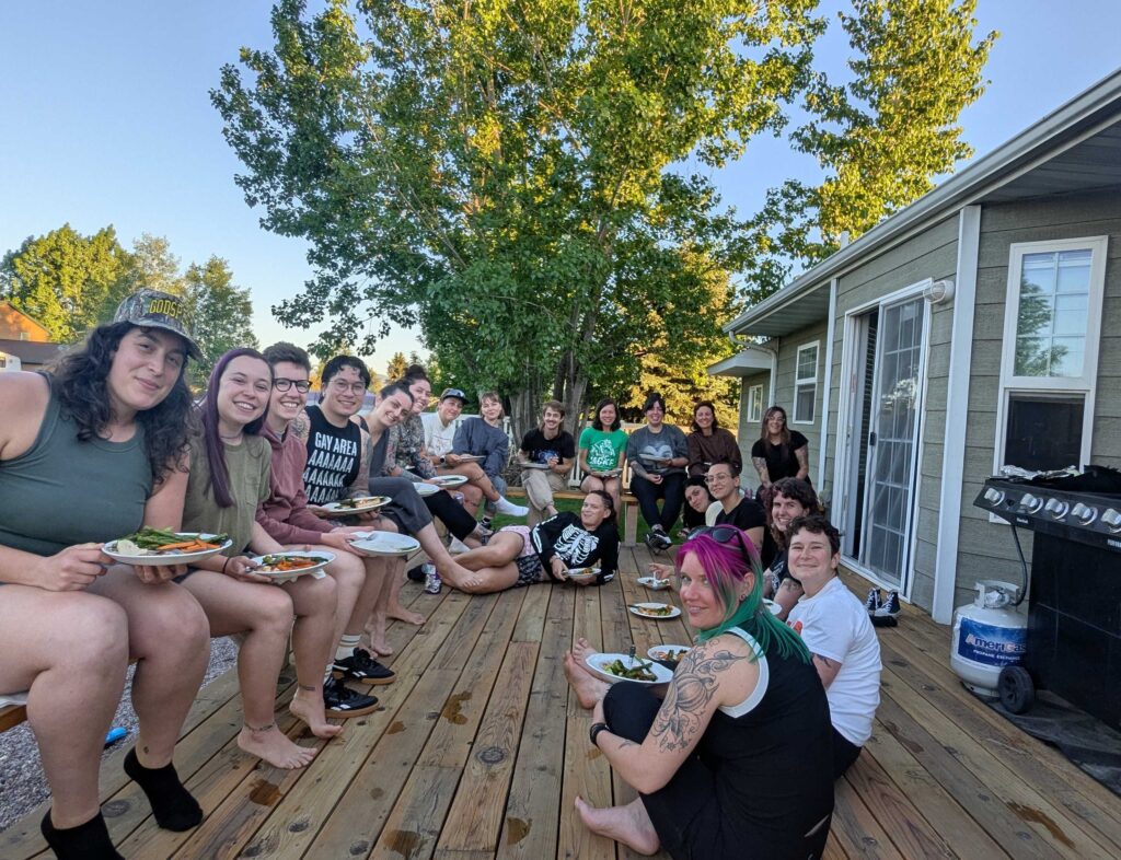 BAD Rocky Mountain Rumble 2025 A group picture of BAD All-Stars sitting on a porch in Montana with plates on their laps.